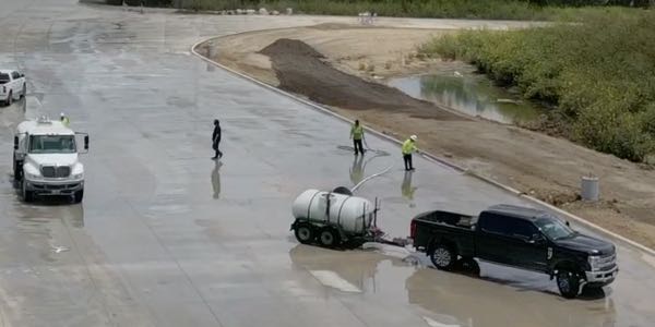 Crews clean a newly finished concrete roadway
